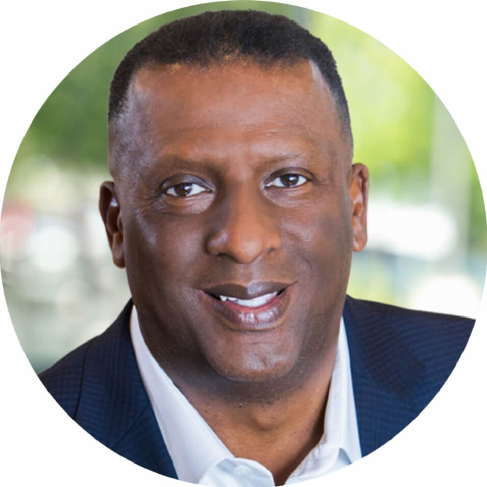 Professional headshot of a smiling man in a blue suit.