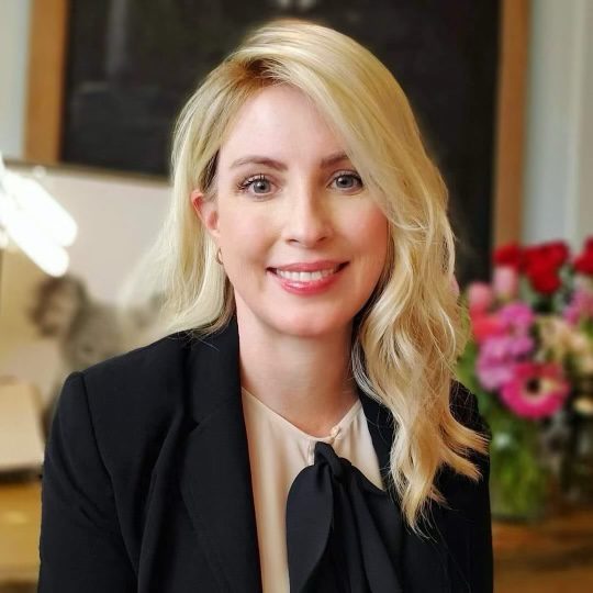 Professional woman with blonde hair smiling.